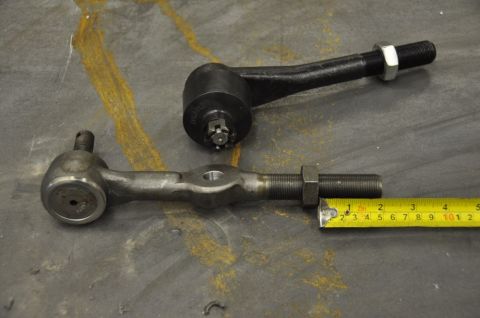 1996 Ford Bronco - Two automotive steering linkage components are shown with a measuring tape for scale.