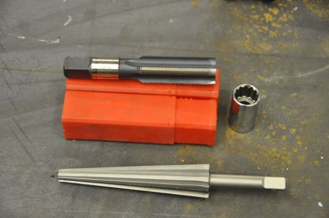 1996 Ford Bronco - Tools for threading and fastening are laid out on a workbench surface.
