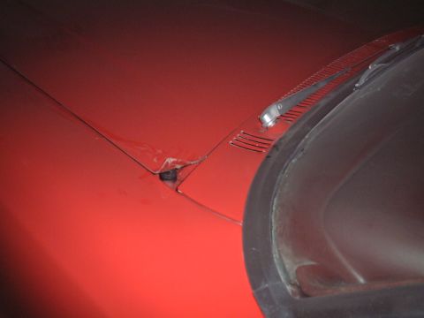 1967 Ford Galaxie - Close-up view of a red car's hood and windshield frame, showing damage to the hood latch area.
