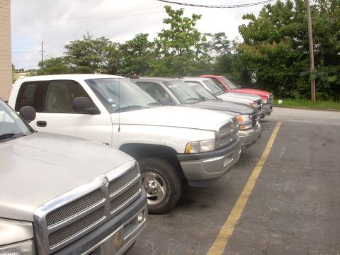 1993 Ford Bronco - Multiple pickup trucks are parked in a line in an outdoor lot.