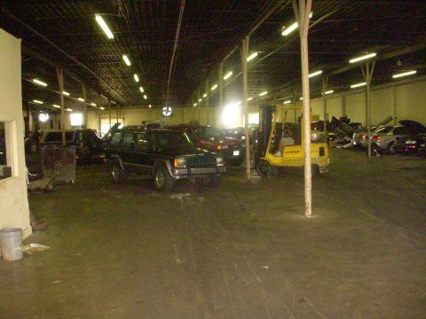 1993 Ford Bronco - Several vehicles are parked inside a large warehouse, with a yellow forklift visible to the right.