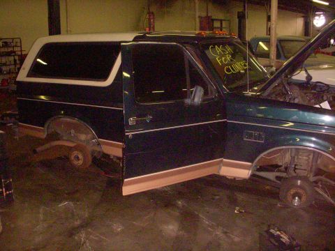 1993 Ford Bronco - This 1993 Ford Bronco is missing its wheels and has its doors and hood open, suggesting it is being worked on or dismantled.