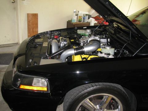 2003 Mercury Marauder - The engine bay of a black car is open, revealing a modified engine with a turbocharger and custom exhaust components.