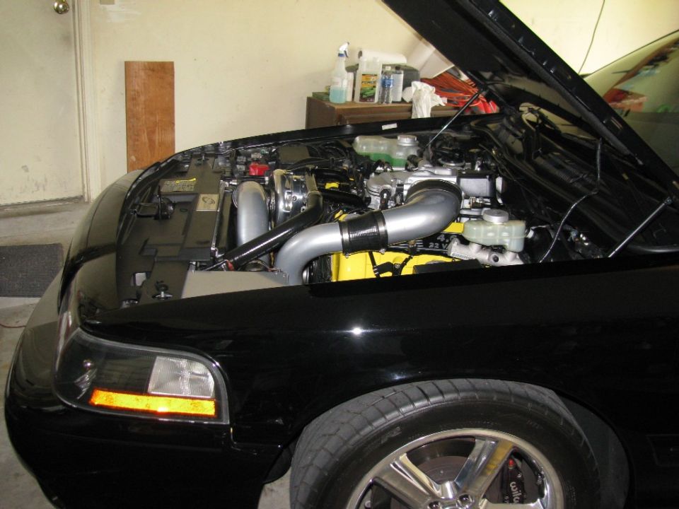 Black car engine bay with turbocharger and custom intake piping