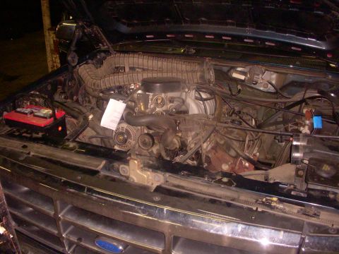 1993 Ford Bronco - The engine bay of a vehicle is shown with the hood up, revealing the engine components and battery.