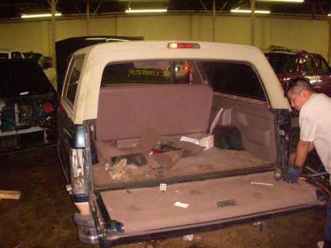 1993 Ford Bronco - A 1993 Ford Bronco is shown from the rear with its tailgate down, revealing the interior cargo area.