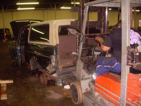1993 Ford Bronco - Forklift moves a 1993 Ford Bronco that is missing a front wheel and has its doors open.