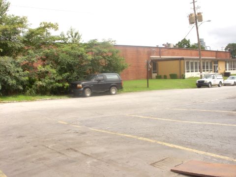 1993 Ford Bronco - A black SUV is parked next to a line of trees, with a white pickup truck and a car visible in the background.