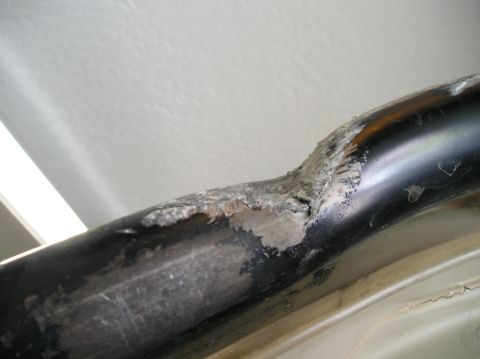 1986 Toyota Hilux - A close-up view shows a damaged black metal bar with exposed metal and chipped paint.