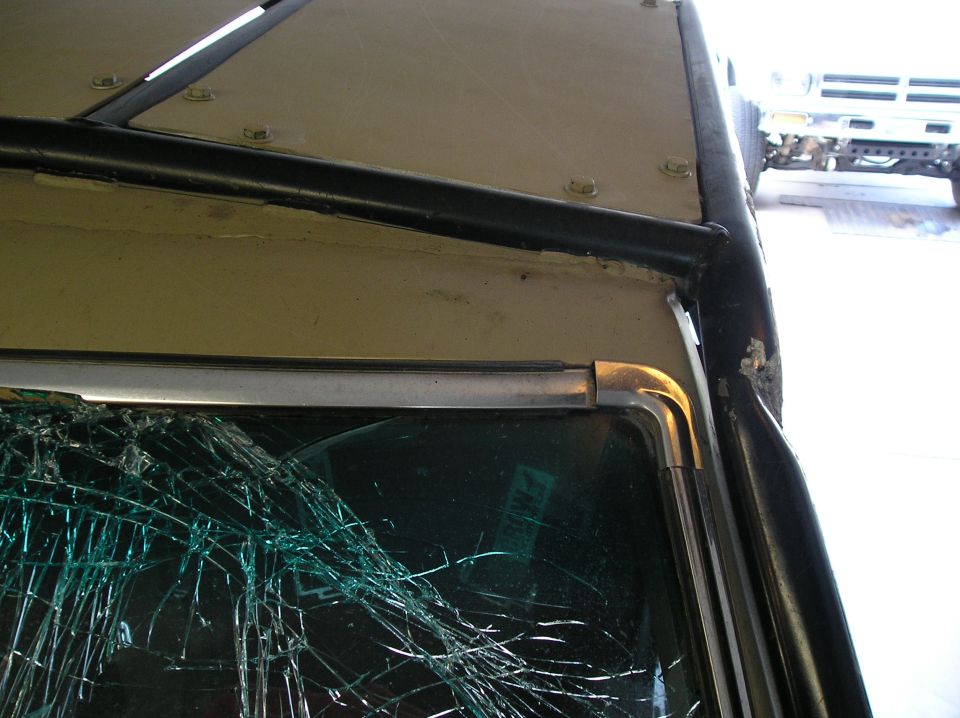 Truck with cracked windshield and roll cage, another truck in background