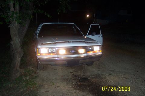 1991 Ford Crown Victoria LTD - Front view of a 1991 Ford Crown Victoria LTD parked on a dirt road at night.