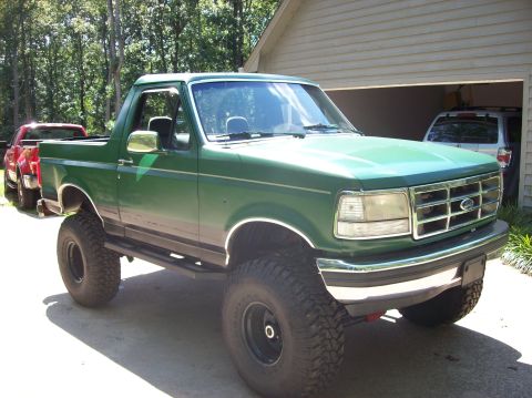 1992 Ford Bronco - Lifted 1992 Ford Bronco in a driveway, with a second vehicle in the garage behind it.