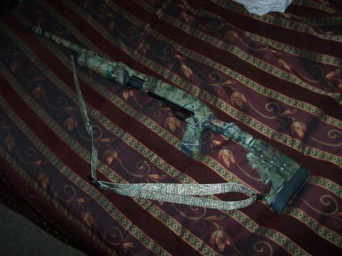 1994 Ford F-150 - A shotgun with a camouflage pattern and a matching sling is displayed on a striped, patterned fabric.