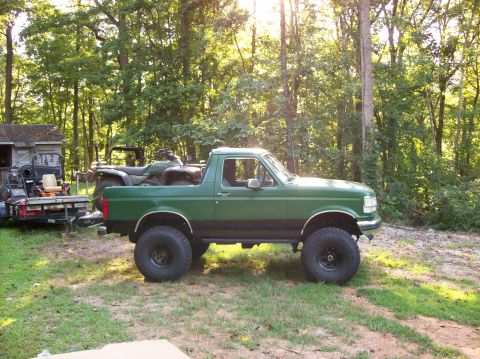 1992 Ford Bronco - Side view of a lifted green 1992 Ford Bronco parked outdoors.