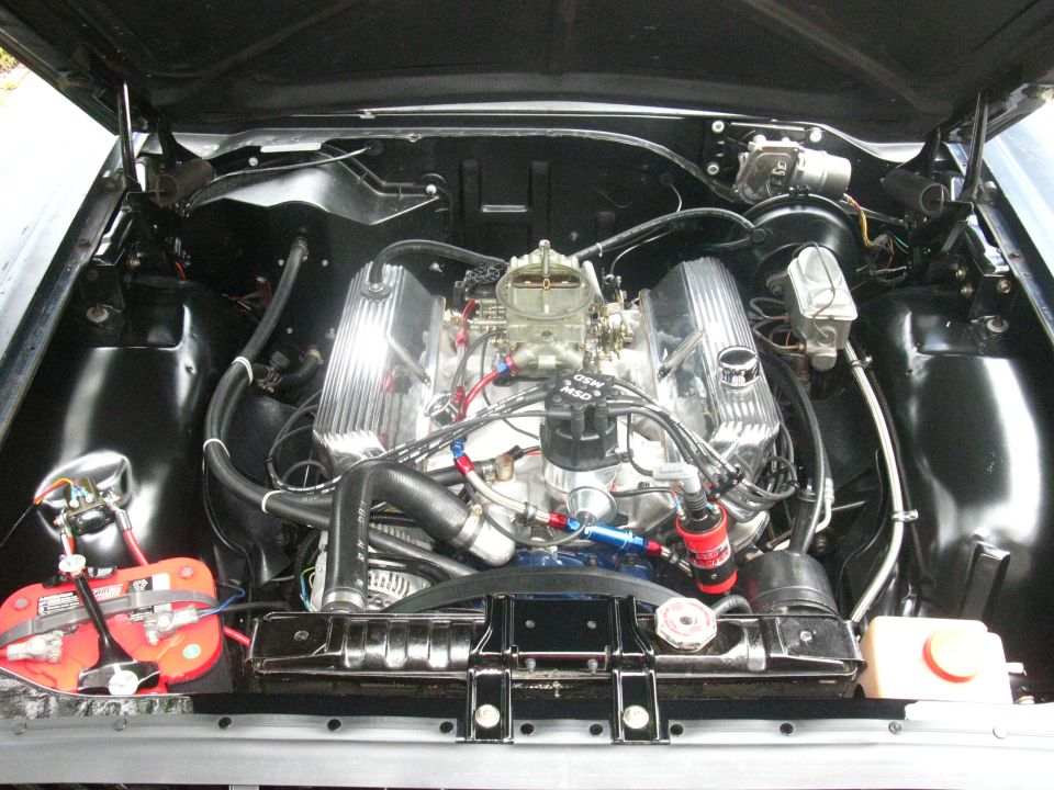 Detailed V8 engine bay with finned valve covers, four-barrel carb, MSD ignition and red-top battery