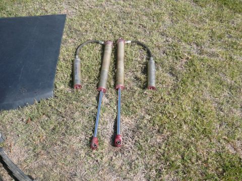 1988 Ford Bronco - Pair of shock absorbers with remote reservoirs, likely aftermarket parts, shown on grass.