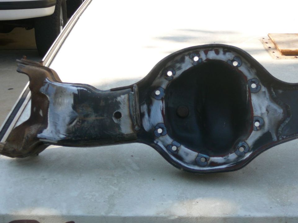 Differential housing with bolt holes around the cover, resting on a concrete surface