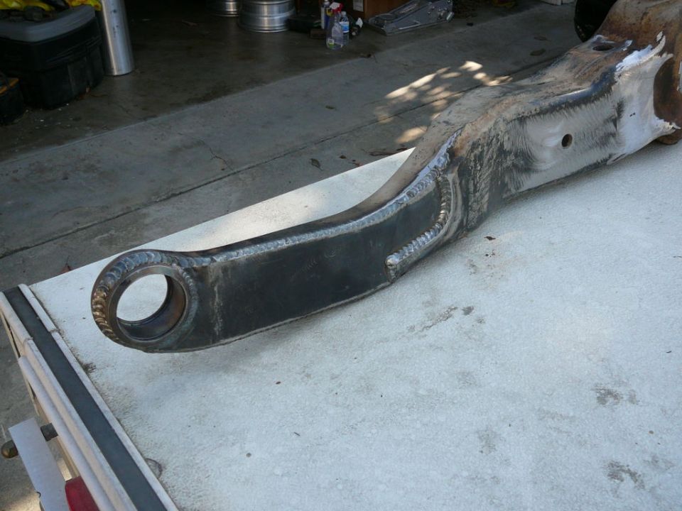 Close-up of a heavy-duty, welded metal suspension part with a large circular opening at one end