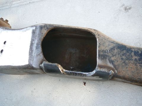 1988 Ford Bronco - A close-up view of a damaged vehicle frame component, showing a large opening and repair welds.