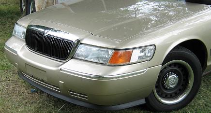 2000 Mercury Grand Marquis - Front view of a gold 2000 Mercury Grand Marquis, showing the grille and headlights. The Supermotors.net watermark is visible.