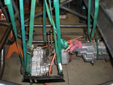 Suzuki Samurai - Two aluminum transmission/transfer case assemblies suspended by green ratchet straps inside a tubular steel chassis, one with a shifter and…