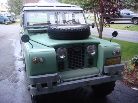 1967 Land Rover Land Rover - A green 1967 Land Rover Land Rover is parked in a driveway, with another Land Rover visible in the background.