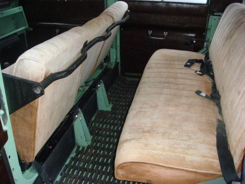 1967 Land Rover Land Rover - Interior view of a vintage vehicle's rear seating area, showing tan upholstery and black seatbelts.
