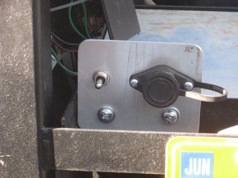 1990 Ford F-250 - Close-up of an aftermarket electrical panel with a switch and a covered connector, mounted on a vehicle's interior or exterior surface.
