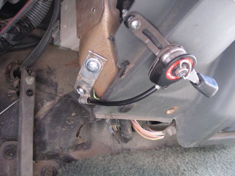 1990 Ford F-250 - Close-up of an interior cable lever mechanism, possibly for a throttle or choke, with visible wiring and mounting hardware.