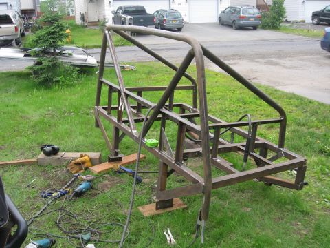 1990 Ford F-250 - A custom-built metal roll cage frame sits on grass, surrounded by tools and equipment.