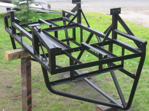 1990 Ford F-250 - A black metal frame, likely for a custom vehicle build, is supported by wooden blocks outdoors.