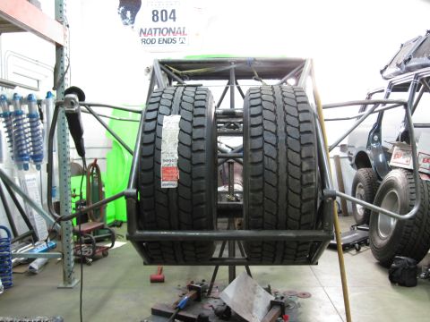 1995 Ford Bronco - Spare tire carrier assembly with two large tires mounted, workshop setting.
