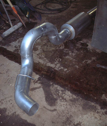 2000 Ford Excursion - A custom exhaust system part is shown lying on a concrete floor, possibly for a truck or SUV.