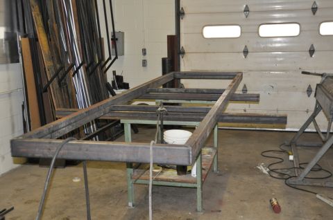 1996 Ford Bronco - A metal frame is being constructed on a workbench in a workshop setting.