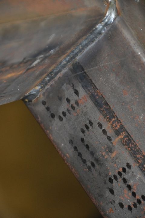 1996 Ford Bronco - Close-up of a welded metal component showing drilled holes and rust.