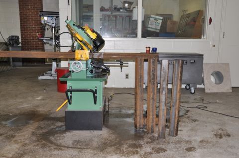 1996 Ford Bronco - Workshop scene with a metal cutting saw, metal stock, and other equipment.