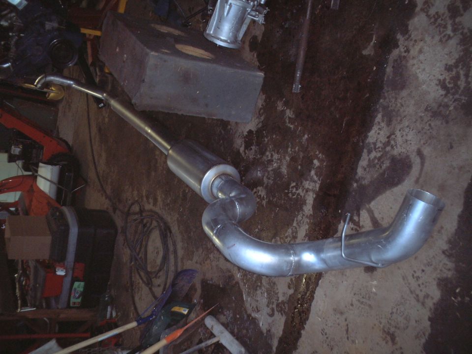 New stainless steel exhaust with muffler and bent pipes on garage floor