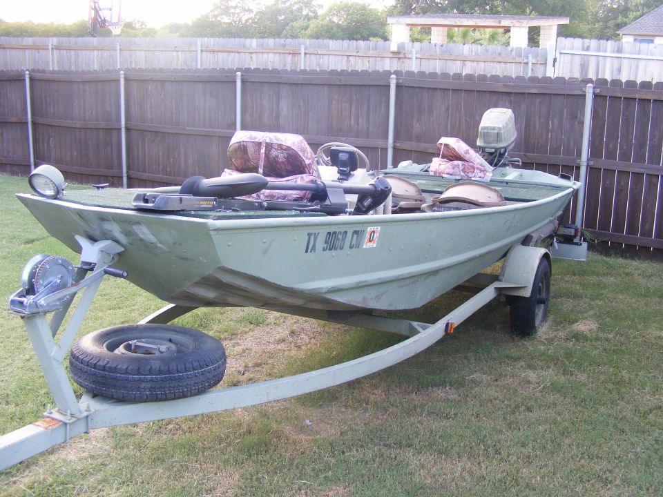 Green jon boat on a trailer with camouflage seat covers and a trolling motor