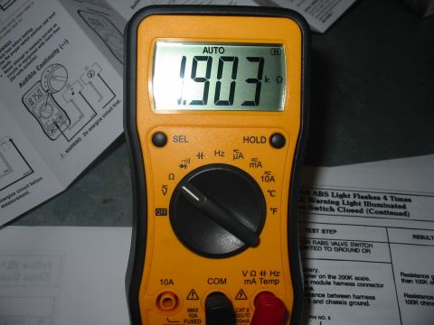 1992 Ford Bronco - A digital multimeter reads 1.903 k ohms, shown with a service manual page detailing ABS light diagnostics.