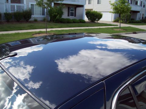 1999 Mercury Grand Marquis - Reflection of apartments and sky on a dark car's roof.