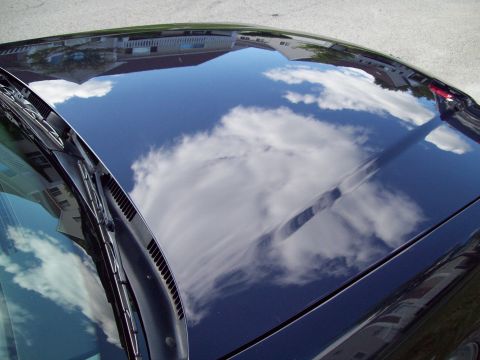 1999 Mercury Grand Marquis - The shiny surface of the car hood reflects the sky and surrounding buildings.