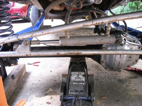 1979 Ford F-150 - Vehicle front axle and steering stabilizer assembly, supported by a 3-ton hydraulic floor jack.