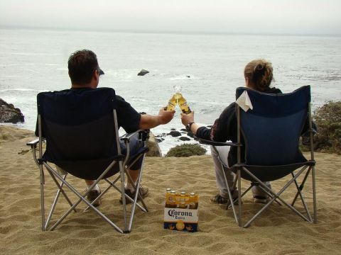 1989 Ford Bronco - A couple enjoys a beer toast on a sandy beach overlooking the ocean.