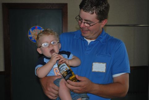 1996 Ford Bronco - Man holds baby wearing glasses and chewing on a Corona Extra bottle.