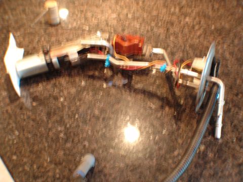 1996 Ford Bronco - A disassembled fuel pump assembly is laid out on a counter, showing its various components and connections.