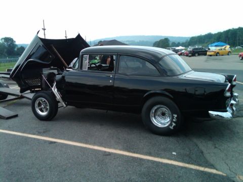 1955 Chevrolet Bel Air - 1955 Chevrolet Bel Air drag car with hood open, parked on asphalt with other vehicles in background.