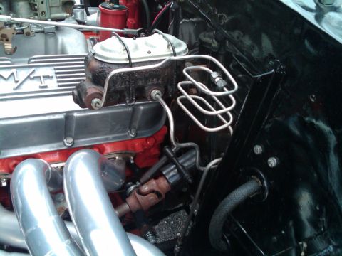 1955 Chevrolet Bel Air - The intricate plumbing and polished components of a classic car's engine bay are visible in this detailed shot.