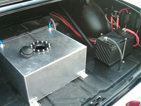 1955 Chevrolet Bel Air - The trunk of a car contains a large aluminum fuel tank and a car battery, with wiring visible.