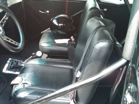 1955 Chevrolet Bel Air - The interior of the car features racing seats, a roll cage, and a helmet, suggesting a performance-oriented build.