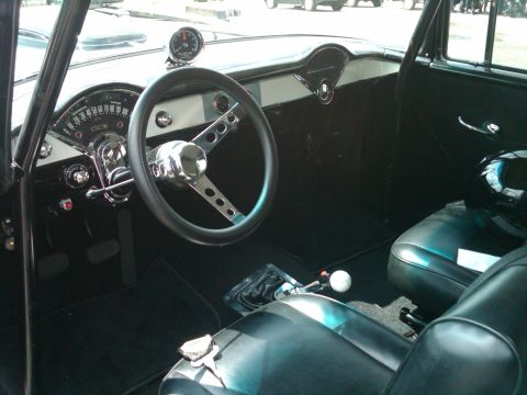 1955 Chevrolet Bel Air - The interior of a 1955 Chevrolet Bel Air features a custom steering wheel, floor shifter, and a tachometer mounted on the dashboard.